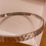 Brazalete tipo esclava de plata 925 con acabado texturado y grabado personalizado en su cara interna.