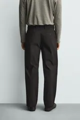 Pantalón de corte regular fit confeccionado en tejido mezcla de algodón. Presenta cintura con detalle de pliegues en el delantero, bolsillos frontales y bolsillos traseros de vivo con botón. Cierre frontal con cremallera y botón.