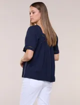 Blusa de corte holgado color marfil, confeccionada en mezcla de modal y algodón, con escote cuadrado y mangas cortas adornadas con detalles de puntilla calada.