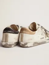 Zapatillas Golden Goose Super-Star de cuero blanco con efecto desgastado, estrella lateral y talón de cuero metalizado dorado, cordones con estampado animal print de leopardo, y detalles manuscritos en la puntera.