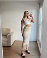 Falda larga de tejido calado color blanco crudo, con detalle de flecos en el dobladillo.