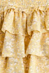 Short pollera mini de viscosa color amarillo con estampado floreado, cintura fruncida y diseño de múltiples volados en capas.
