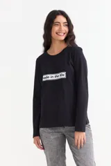 Remera de manga larga color negro con cuello redondo a la base y estampa frontal rectangular con el texto 'made in the 90s'.