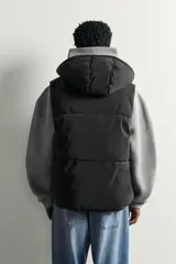 Chaleco acolchado puffer color negro para hombre, de corte regular fit, con capucha ajustable, cierre frontal de cremallera y bolsillos laterales de vivo.