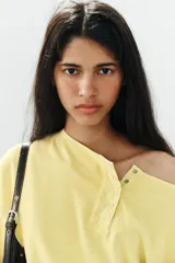 Sudadera de algodón con efecto lavado en color amarillo, cuello barco, abertura frontal con botones a presión y manga larga.