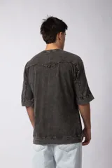 Remera de corte oversize con efecto de lavado gastado, confeccionada en algodón pesado. Presenta cuello redondo, mangas cortas con costuras visibles y un diseño amplio.