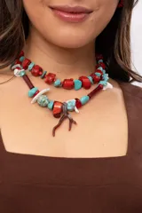 Collar corto elaborado con cuentas de turquesa reconstituida, piezas de nácar blanco, cuentas de cristal rojo y turquesa, y un dije central con forma de rama de coral.