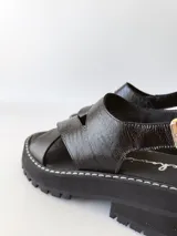 Sandalias negras de cuero con tiras cruzadas, plataforma track y hebilla lateral.