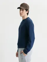 Sweater de punto inglés con escote redondo y mangas largas. Presenta cuello y puños terminados en punto canalé.