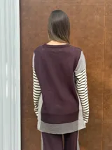 Conjunto de dos piezas en tejido de punto color beige, compuesto por un sweater de calce relajado con mangas a rayas y un pantalón de tiro alto con caída suelta y detalle lateral a rayas.