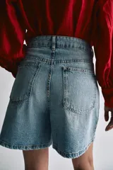 Shorts de denim de tiro alto y corte relaxed fit de Zara Woman Collection, en color celeste con lavado claro. Presenta trabillas en la cintura, cinco bolsillos, detalles de pliegues frontales y cierre con cremallera y botón metálico.