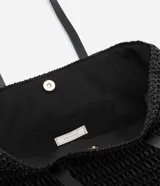 Bolso de playa tejido en paja de papel color negro, con asas de cuero sintético y cierre a presión. Incluye borla decorativa colgante.