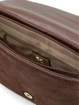 Cartera tipo bandolera de cuero gamuzado en color marrón chocolate, con solapa frontal y cierre mediante hebilla decorativa con broche a presión. Incluye correa ajustable y detalles en herrajes dorados.
