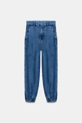 Pantalón de jean estilo bombacho con tiro medio, confeccionado en denim azul con costuras verticales decorativas y puños ajustados en el ruedo.