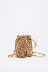 Minibolso tipo saco Bimba y Lola de diseño trenzado metalizado en color dorado, con cierre de cordón ajustable y correa fina trenzada para el hombro. Incluye parche con logo grabado en el frente.