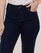 Pantalón capri de jean azul con calce ajustado, tiro alto, cinco bolsillos, cierre frontal con botón y pequeños tajos en los ruedos.