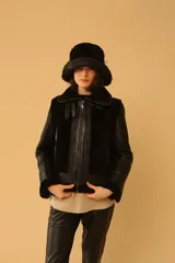 Campera tipo gamulán de cuero negro con interior y detalles en piel sintética negra, cierre frontal y cuello con hebillas ajustables.