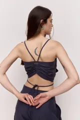 Blusa crop azul marino con tirantes finos y detalle de nudo frontal con forma de flor, con tiras para atar en la cintura.