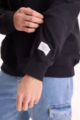 Buzo canguro oversize negro sin friza, con capucha, bolsillo delantero tipo canguro y pequeño estampado blanco en el pecho con la inscripción "Summer Culture".