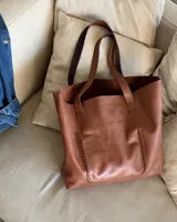 Bolso tote negro de cuero vacuno con costuras a la vista.