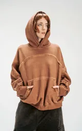 Hoodie oversize color beige con efecto batik, costuras expuestas y recortes estructurales. Presenta capucha amplia y bolsillo frontal tipo canguro.