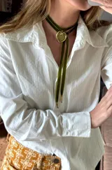 Colgante de estilo choker compuesto por una cinta de terciopelo verde con un dije de corazón en bronce y una cadena de cuentas de piedra natural en tonos verdes y rosados.