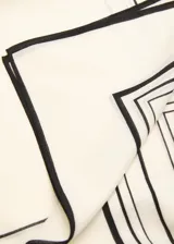 Fular cuadrado de lana con estampado geométrico de líneas negras sobre fondo color crema.