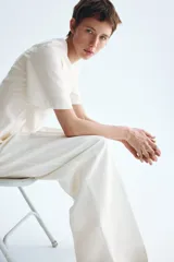 Blusa blanca de manga corta con escote redondo, costuras moldeadoras y diseño peplum acampanado con cierre trasero de botón.