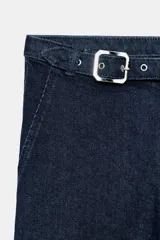 Jeans de tiro medio en denim azul oscuro, con diseño capri de pernera entallada. Presenta cierre frontal con cremallera y botón, y un cinturón integrado con hebilla metálica en la cintura.
