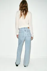 Jeans de tiro medio, corte loose straight, color celeste claro con efecto de salpicaduras de pintura en varios colores. Cierre frontal con cremallera y botón, y diseño de cinco bolsillos.