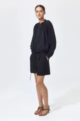 Short negro de tiro alto en mezcla de lino, algodón y viscosa, con pliegues frontales y posteriores, bolsillos al bies y bajos con vuelta cosida.