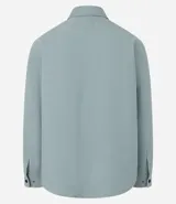 Camisa de manga larga confeccionada en sarga de algodón color verde menta, con cuello inglés y cierre frontal de botones negros. Presenta dos bolsillos de parche con solapa en el pecho y puños con botones.