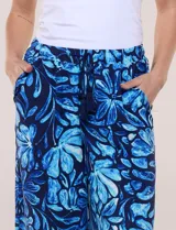 Pantalón de poliéster de corte ancho tipo palazzo y calce relajado, con estampado de hojas en tonos azules, cintura alta elastizada con cordón ajustable y bolsillos laterales.