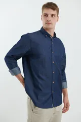 Camisa de jean azul oscuro de manga larga con cuello abotonado y bolsillo en el pecho.
