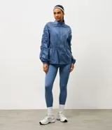 Campera deportiva tipo parka de microfibra en color azul, con cuello alto, cierre frontal por cremallera y mangas largas con puños elásticos. Presenta un diseño con fruncido lateral ajustable y corte amplio.