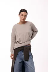 Sweater de silueta amplia y largo medio, con cuello redondo, mangas largas y detalle de botones decorativos en los laterales. Presenta un diseño de tejido de punto con caída relajada.