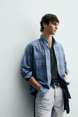 Camisa de corte regular fit confeccionada en tejido ligero de algodón, con estampado de cuadros en tonos azules y grises. Presenta cuello abotonado, manga larga con puños abotonados, bolsillo plastrón en el pecho y cierre frontal de botones.