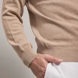 Polera color beige de tejido de punto con cuello alto.