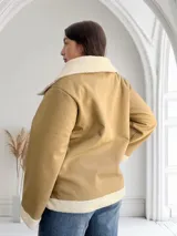 Campera color beige de ecocuero con interior de corderito blanco, cierre frontal con cremallera y bolsillos laterales.