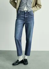 Jeans de tiro alto con corte mom-fit, confeccionados en tejido de algodón estilo vaquero. Presentan cierre de cremallera y botón, trabillas para cinturón y diseño clásico de cinco bolsillos.