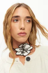 Gargantilla con cordones finos negros y dije de flor de tela blanca con contorno y centro bordados en negro.