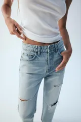 Jeans wide leg de tiro alto y cinco bolsillos, confeccionados en denim con lavado azul medio y efecto desgastado. Presenta cierre frontal con cremallera y botón metálico.