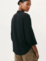 Blusa color marrón claro, con cuello mao y escote en V, manga 7/8 con puños elásticos y cierre frontal parcial con botones.