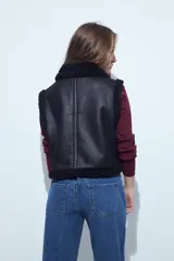 Chaleco de símil cuero negro con interior y detalles de corderito sintético. Presenta cierre frontal y bolsillos laterales con cierre.