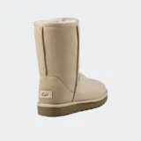 Botas de caña media UGG Classic Short II, confeccionadas en piel de oveja de doble cara color beige, con forro interior de lana suave y suela exterior liviana para mayor amortiguación.