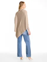 Poncho de tejido con lurex, de corte asimétrico y cuello recto. Presenta mangas tipo japonesa con puños acanalados.