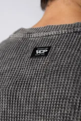 Buzo de corte oversize confeccionado en tela waffle de algodón con proceso de teñido acid wash. Presenta cuello redondo con detalle de costura en X y mangas largas con puños acanalados.