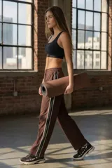 Pantalón deportivo de corte recto y tiro medio, color marrón con franjas laterales en contraste negro y blanco. Confeccionado en tejido de algodón con textura tipo mesh.