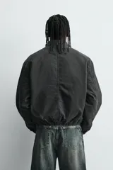 Cazadora de denim acolchada en color negro con efecto lavado. Presenta un corte boxy fit, cuello solapa, cierre frontal con cremallera, bolsillo con cierre en el pecho y bajo elástico.