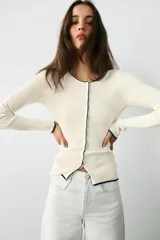 Chaqueta de punto marrón con cuello redondo, manga larga y ribetes en color rojo. Cuenta con cierre frontal de botones.